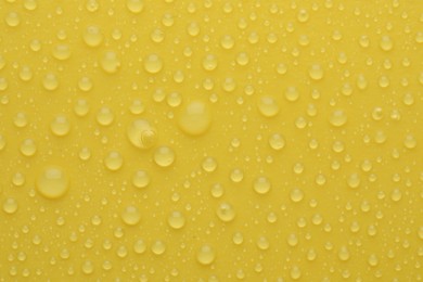 Water drops on yellow background, top view