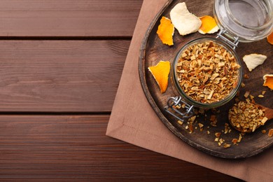 Photo of Tray with jar of dried orange zest seasoning on wooden table, flat lay. Space for text