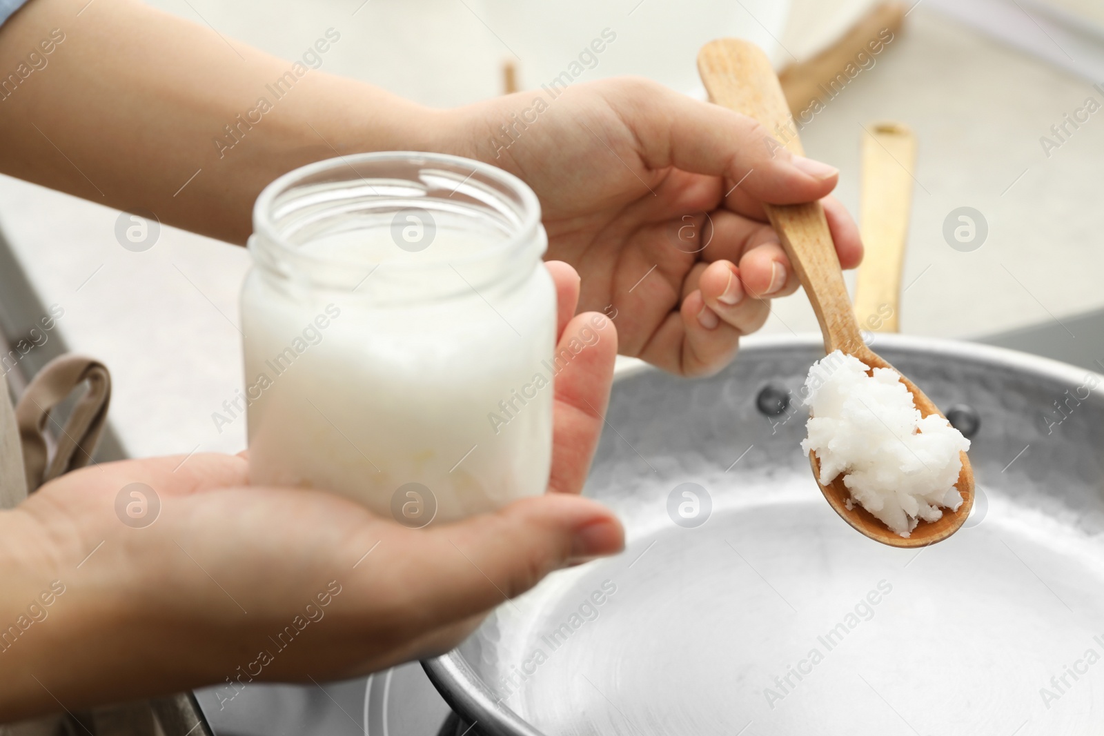 Photo of Woman cooking with coconut oil on induction stove, closeup