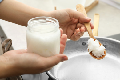 Photo of Woman cooking with coconut oil on induction stove, closeup