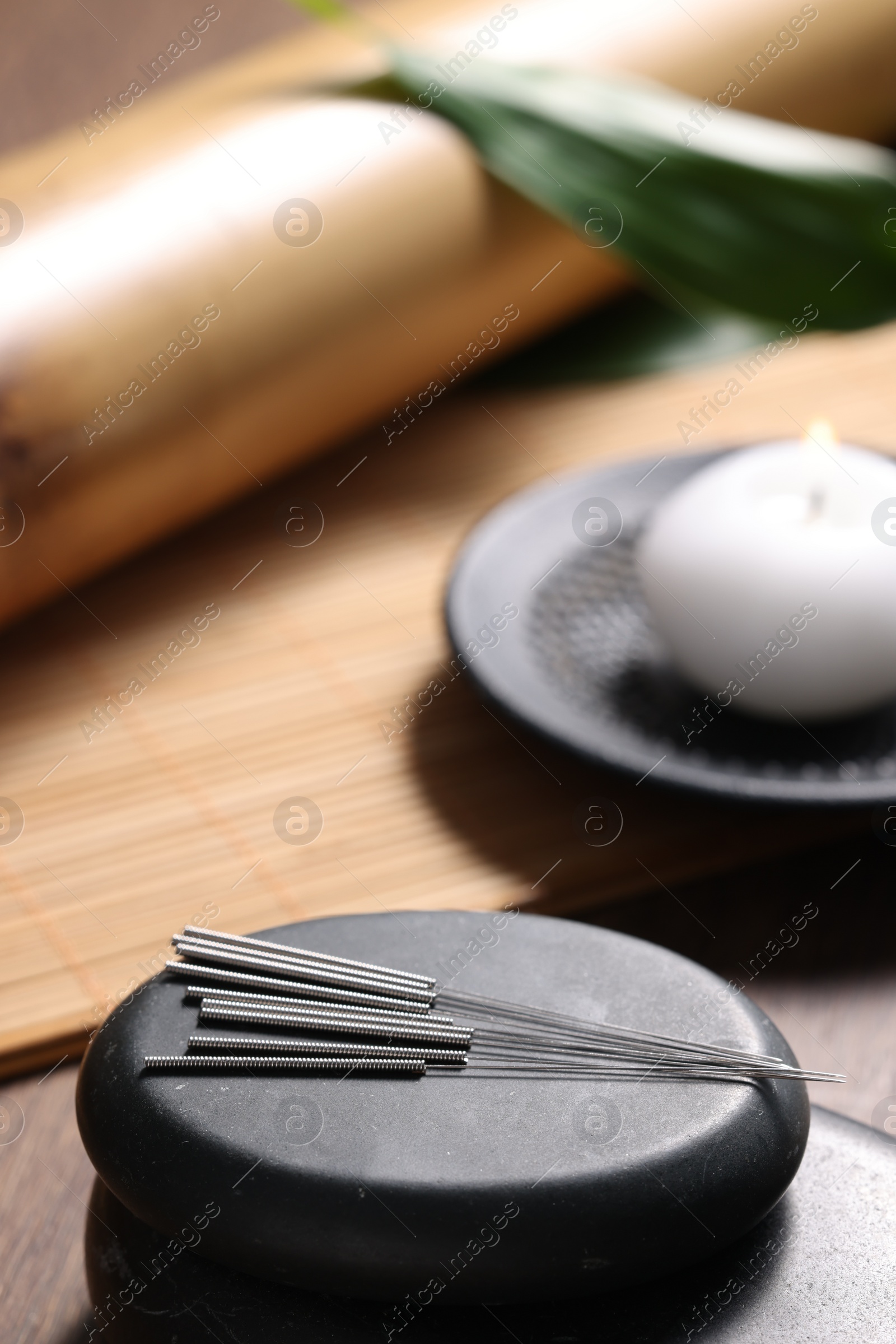 Photo of Stones with acupuncture needles on wooden table