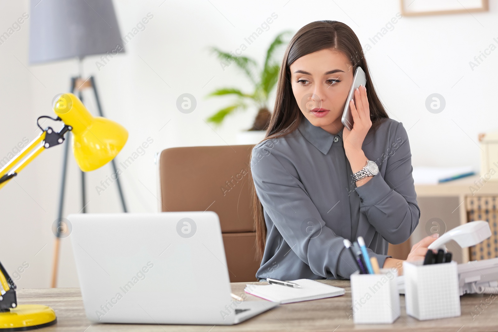 Photo of Young woman talking on phone at workplace