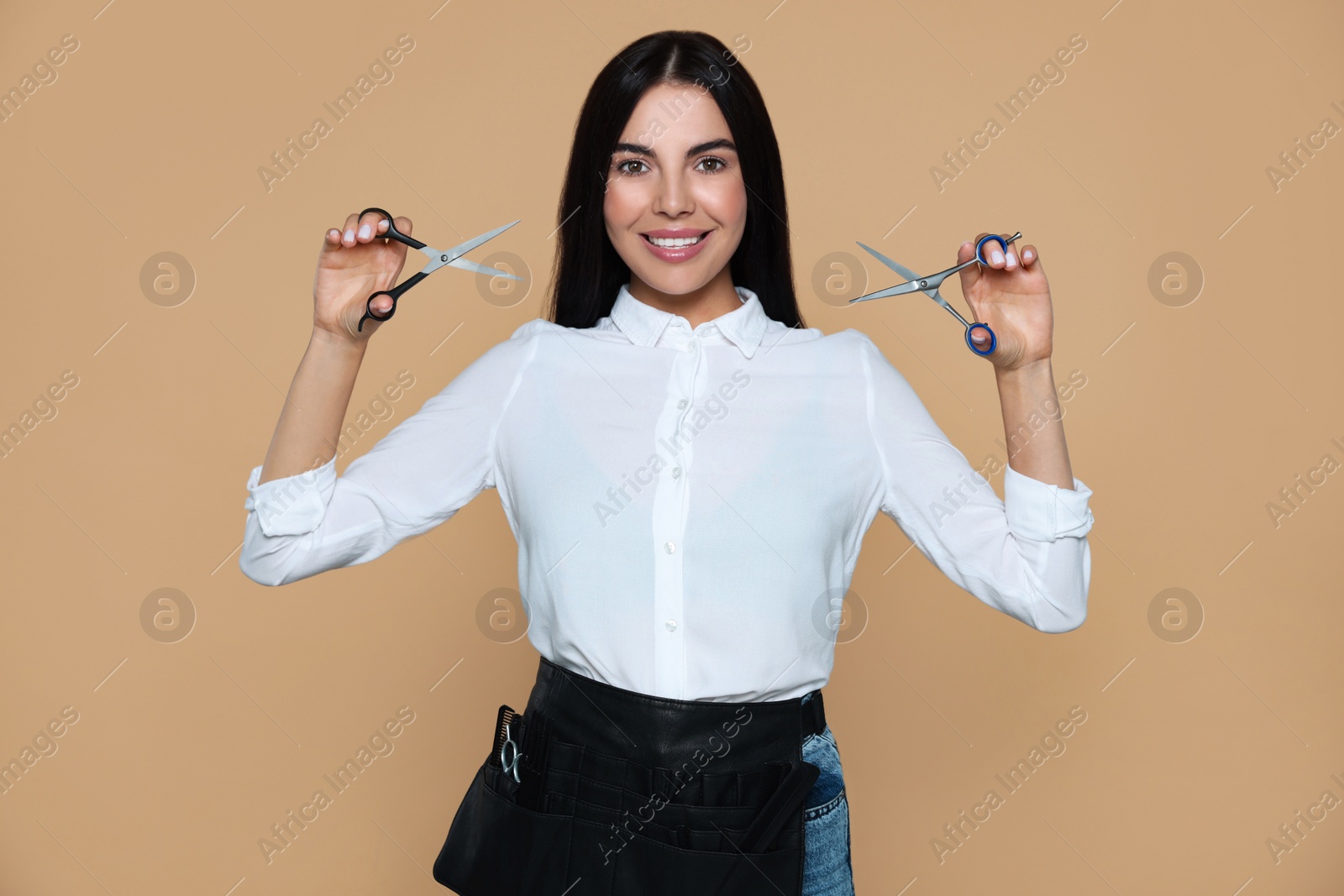 Photo of Portrait of happy hairdresser with professional scissors on beige background