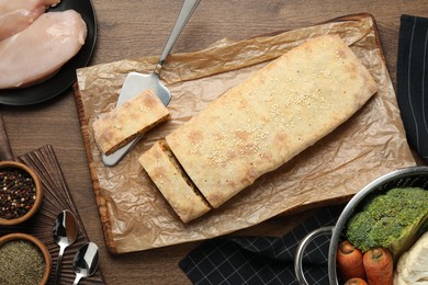 Photo of Delicious strudel with chicken and vegetables served on wooden table, flat lay