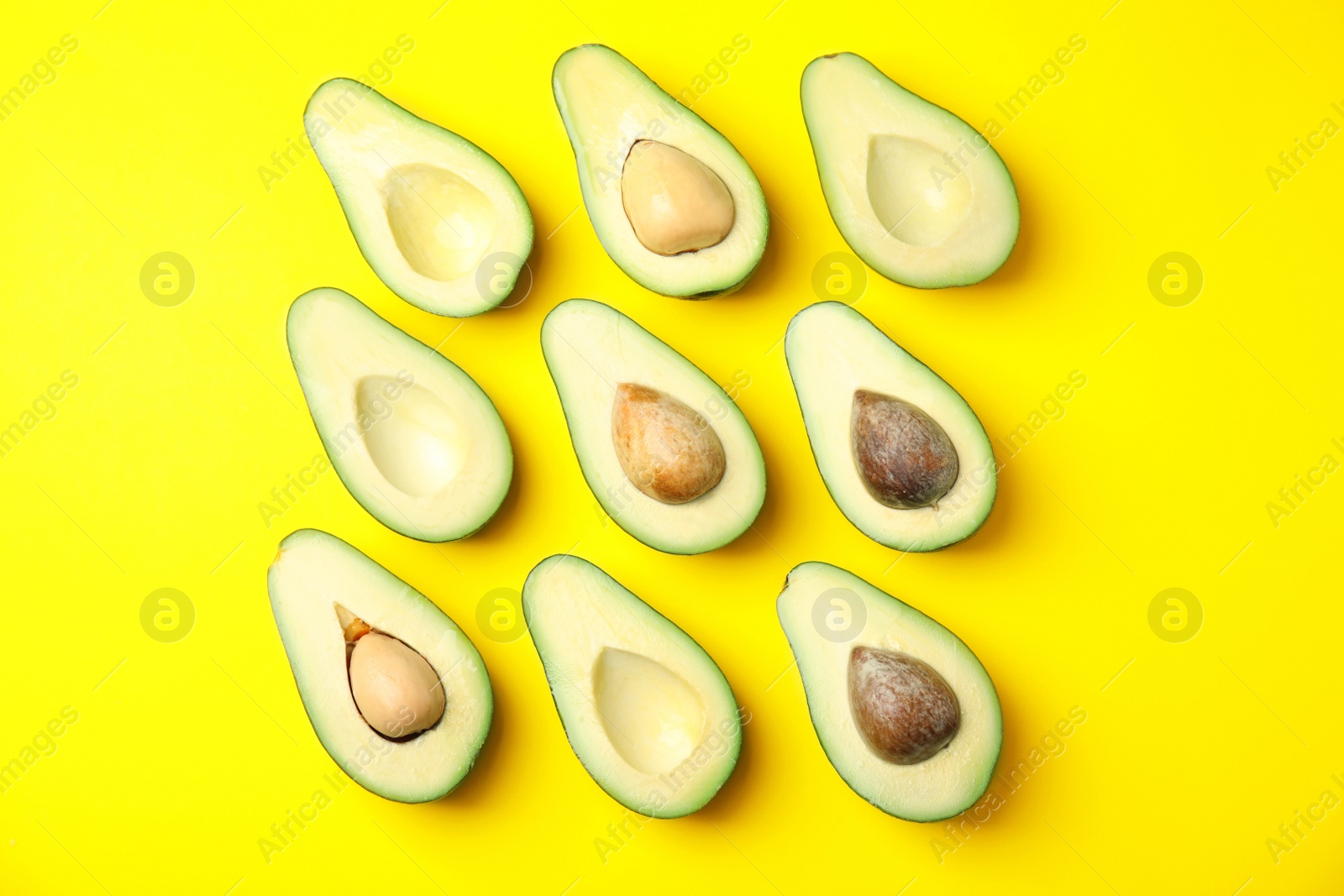 Photo of Cut fresh ripe avocados on yellow background, flat lay