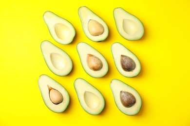 Cut fresh ripe avocados on yellow background, flat lay