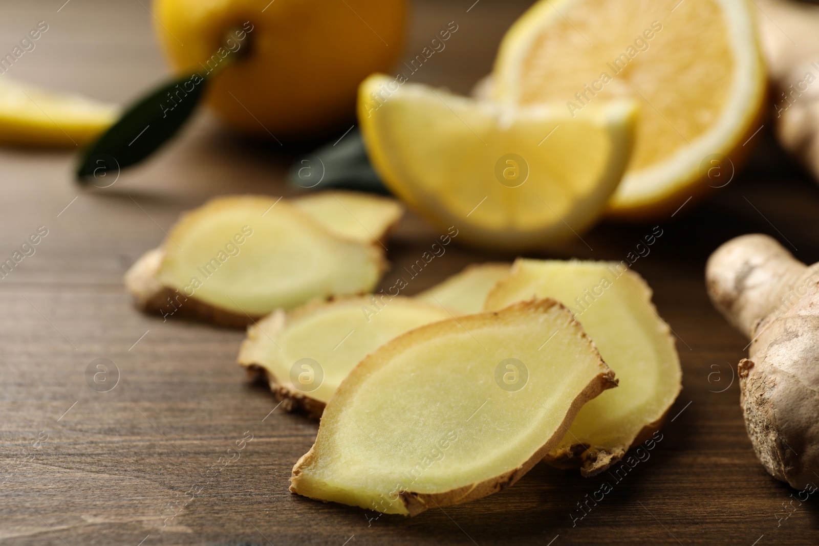 Photo of Cut ginger and lemon on wooden table, closeup