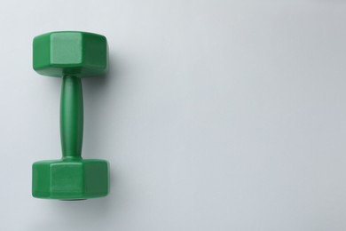 Photo of Green vinyl dumbbell on light background, top view. Space for text