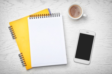 Photo of Flat lay composition with notebooks, smartphone and cup of coffee on light background