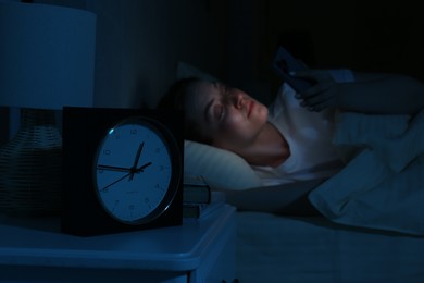 Photo of Woman using smartphone on bed at night, selective focus. Internet addiction