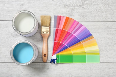 Photo of Flat lay composition with cans of paint and decorator tools on wooden background