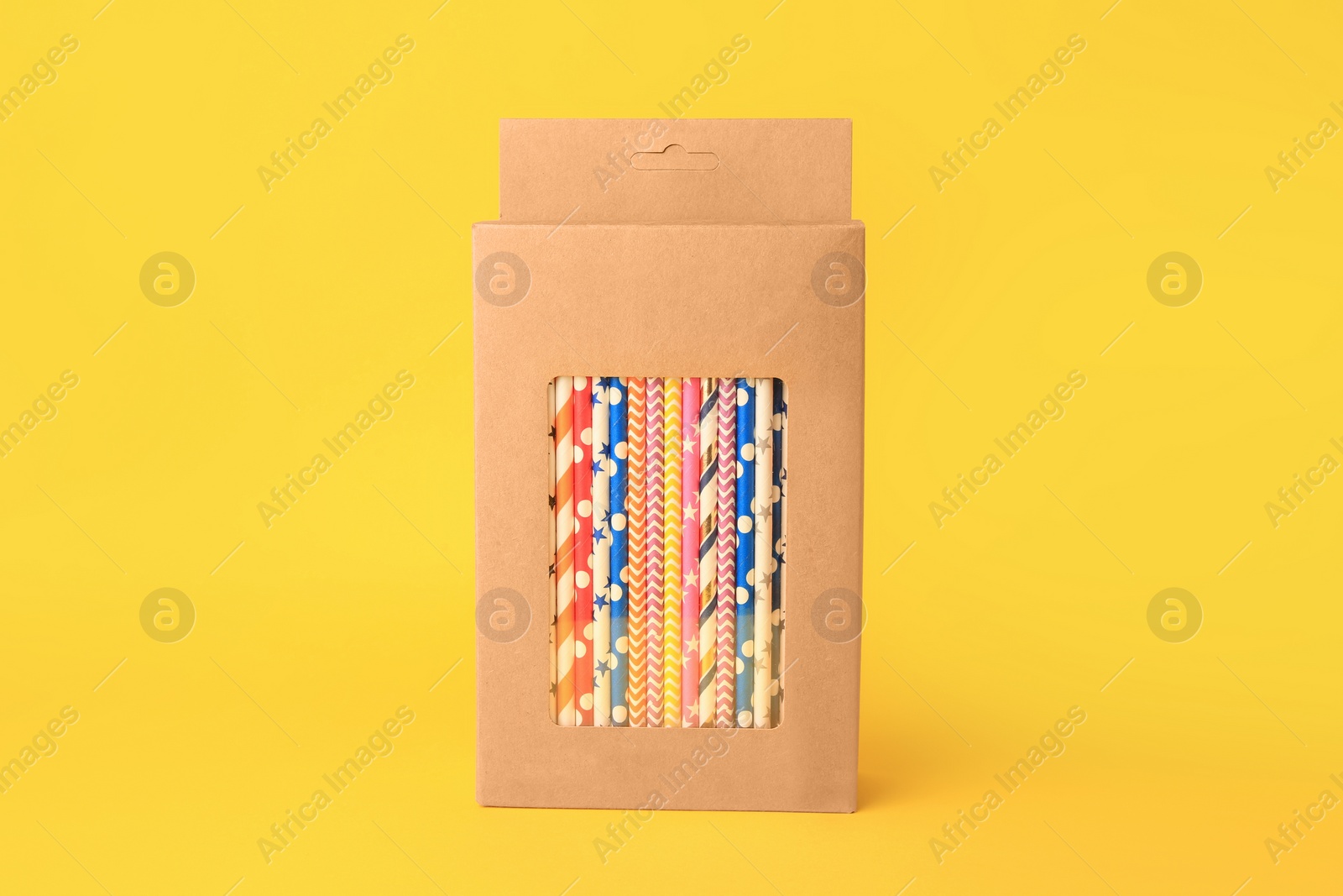 Photo of Box with many paper drinking straws on orange background