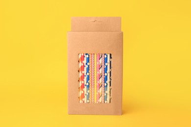 Photo of Box with many paper drinking straws on orange background