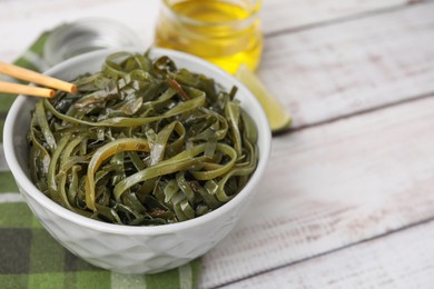 Photo of Tasty seaweed salad in bowl served on wooden table, closeup