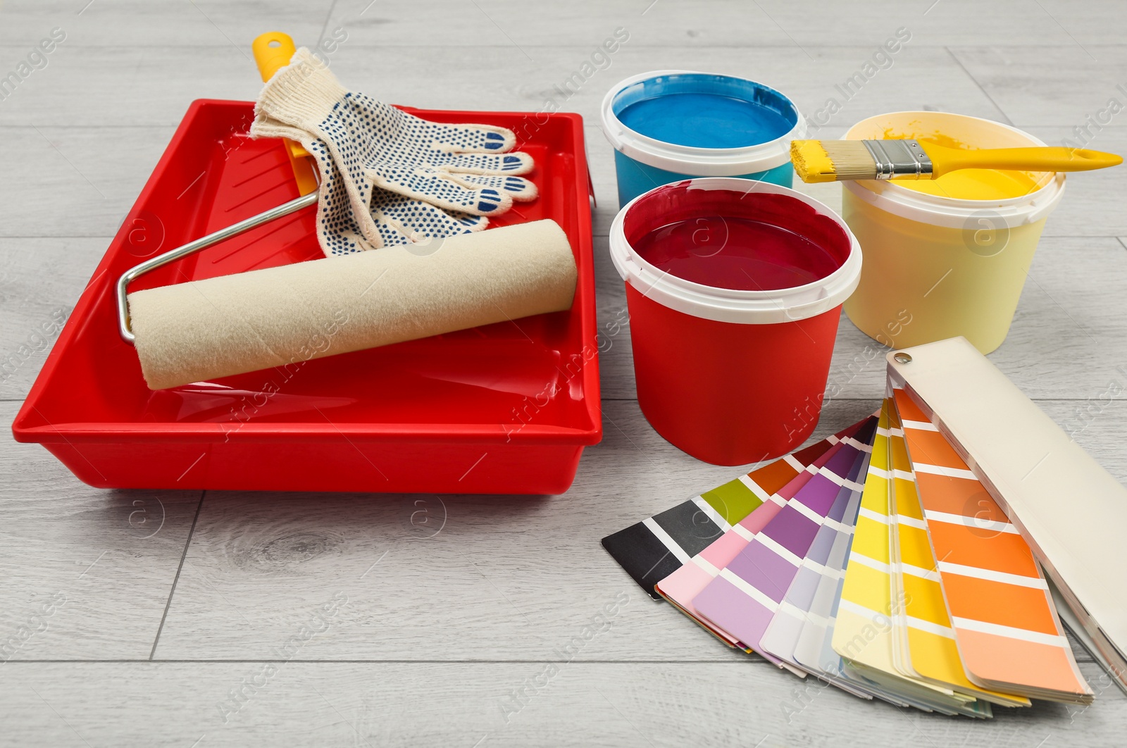 Photo of Buckets of paints, palette and decorator's tools on light wooden background