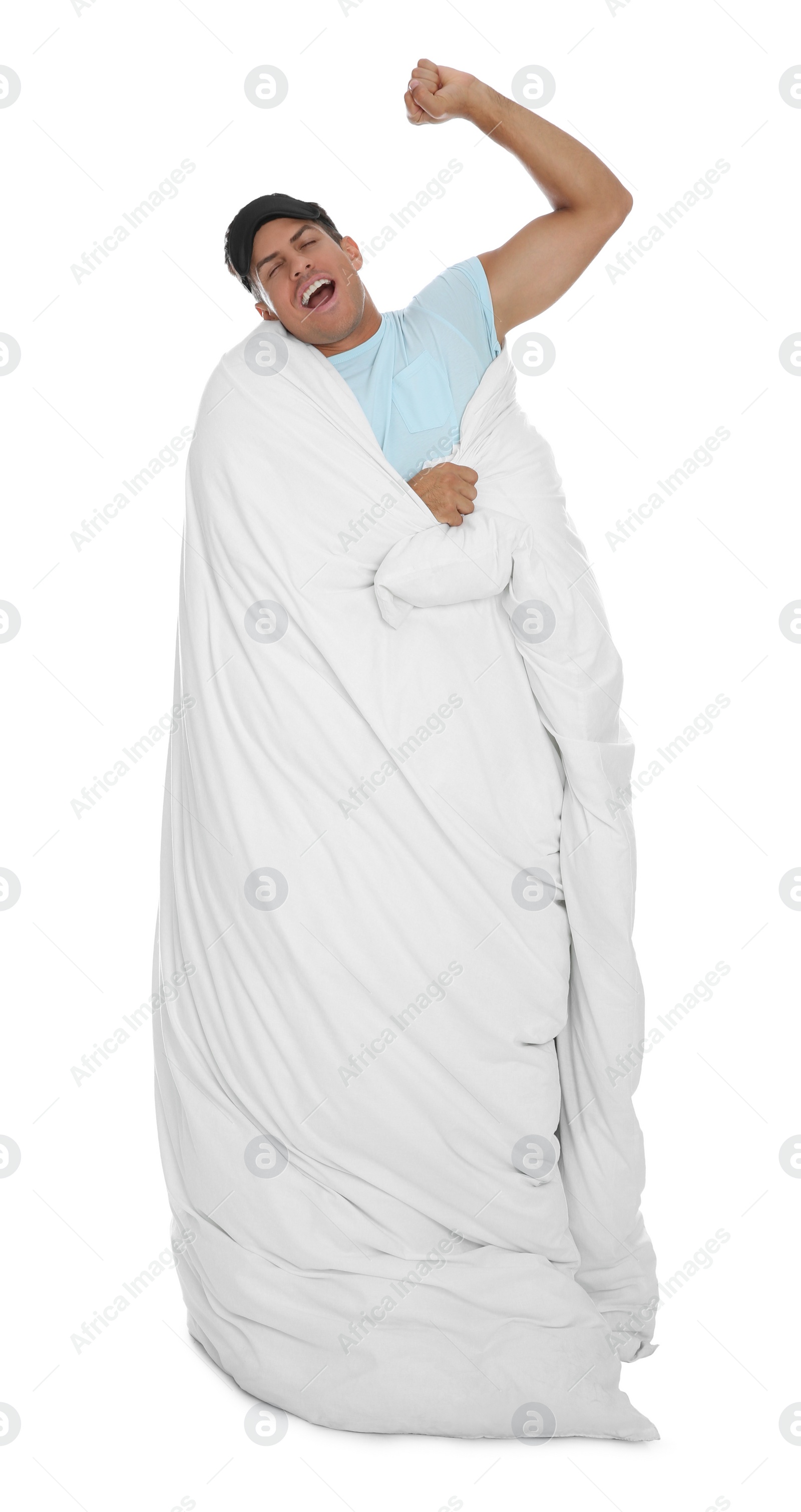 Photo of Man in sleeping mask wrapped with blanket yawning on white background