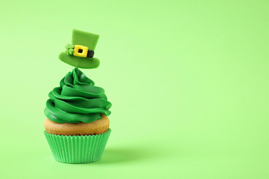 Photo of Delicious decorated cupcake on light green background, space for text. St. Patrick's Day celebration