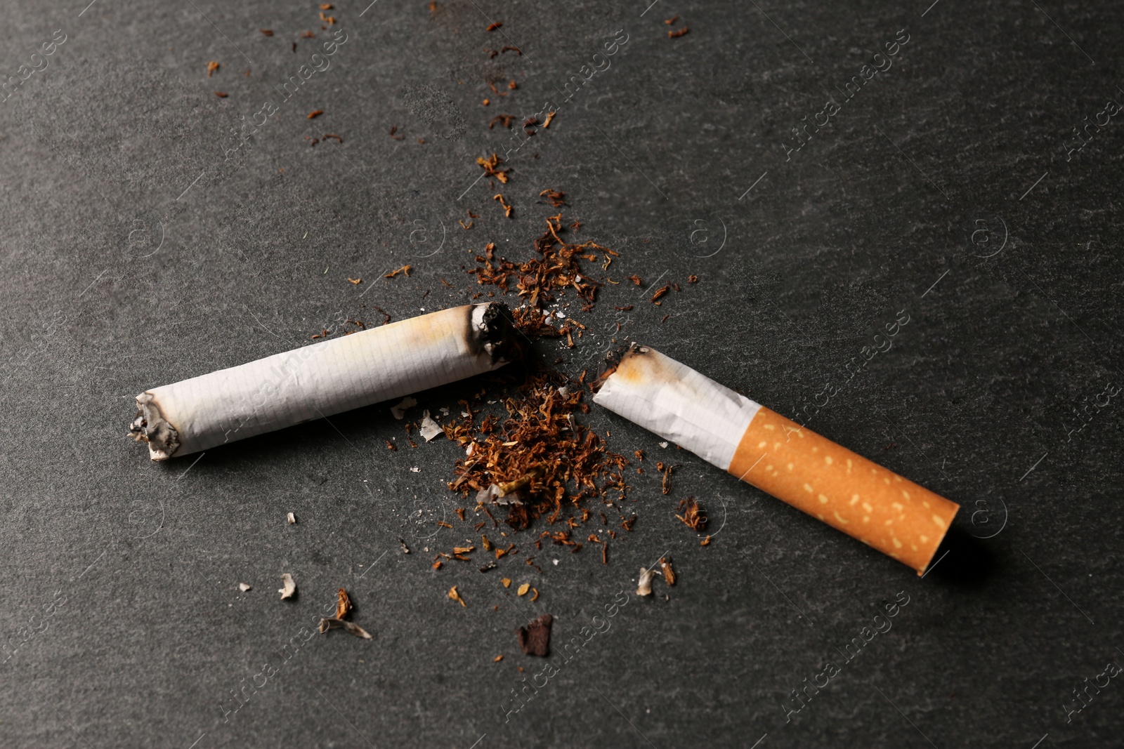 Photo of Burnt cigarette, tobacco and smoke on black table, above view. No smoking concept