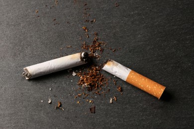 Burnt cigarette, tobacco and smoke on black table, above view. No smoking concept