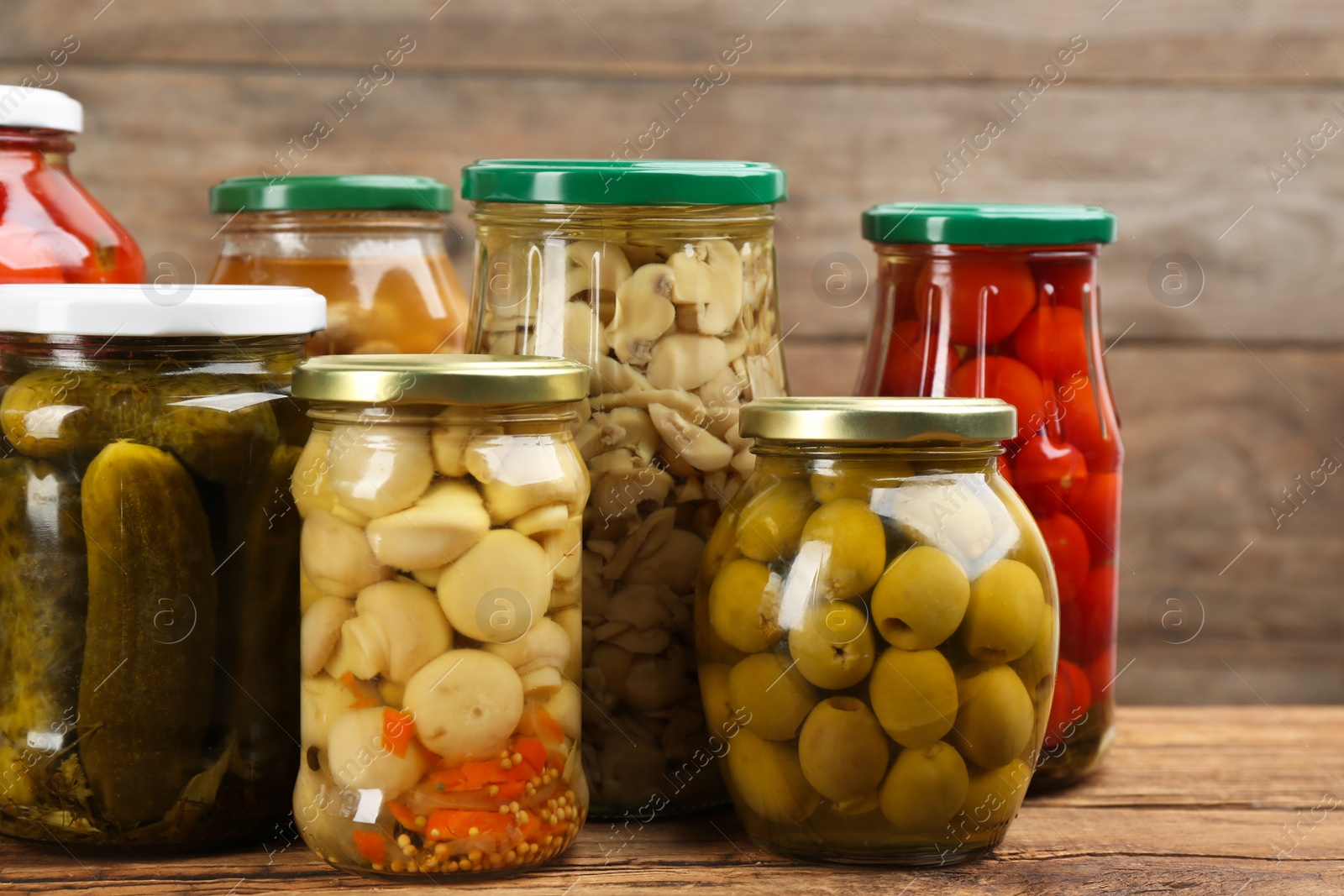 Photo of Jars of pickled vegetables on wooden table, closeup