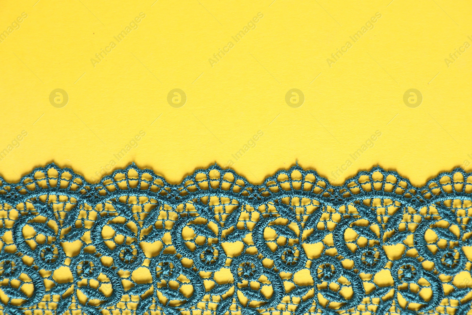 Photo of Green lace on yellow background, top view. Space for text