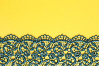 Photo of Green lace on yellow background, top view. Space for text