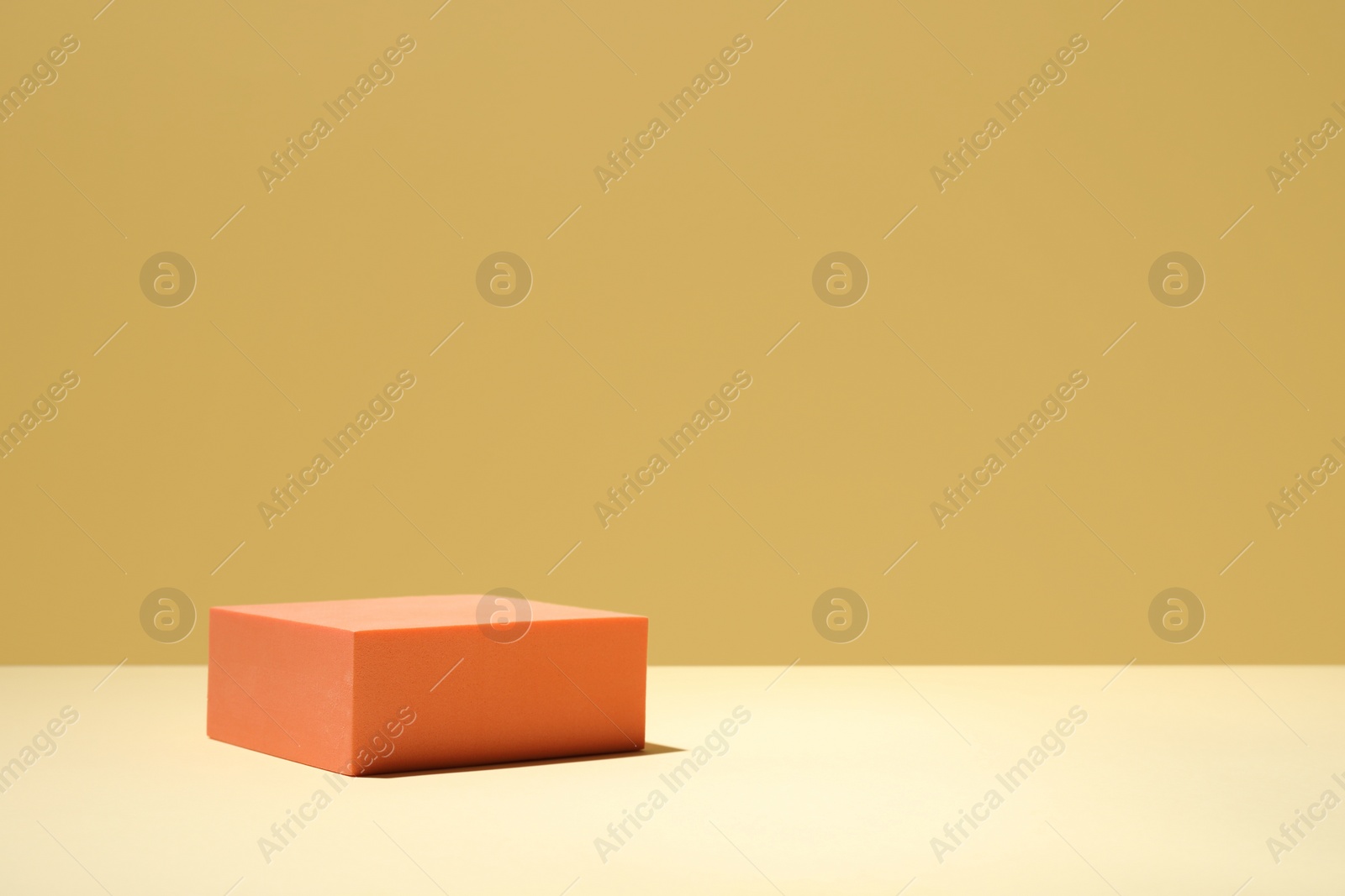 Photo of Orange stand on table against yellow background, space for text. Stylish presentation for product