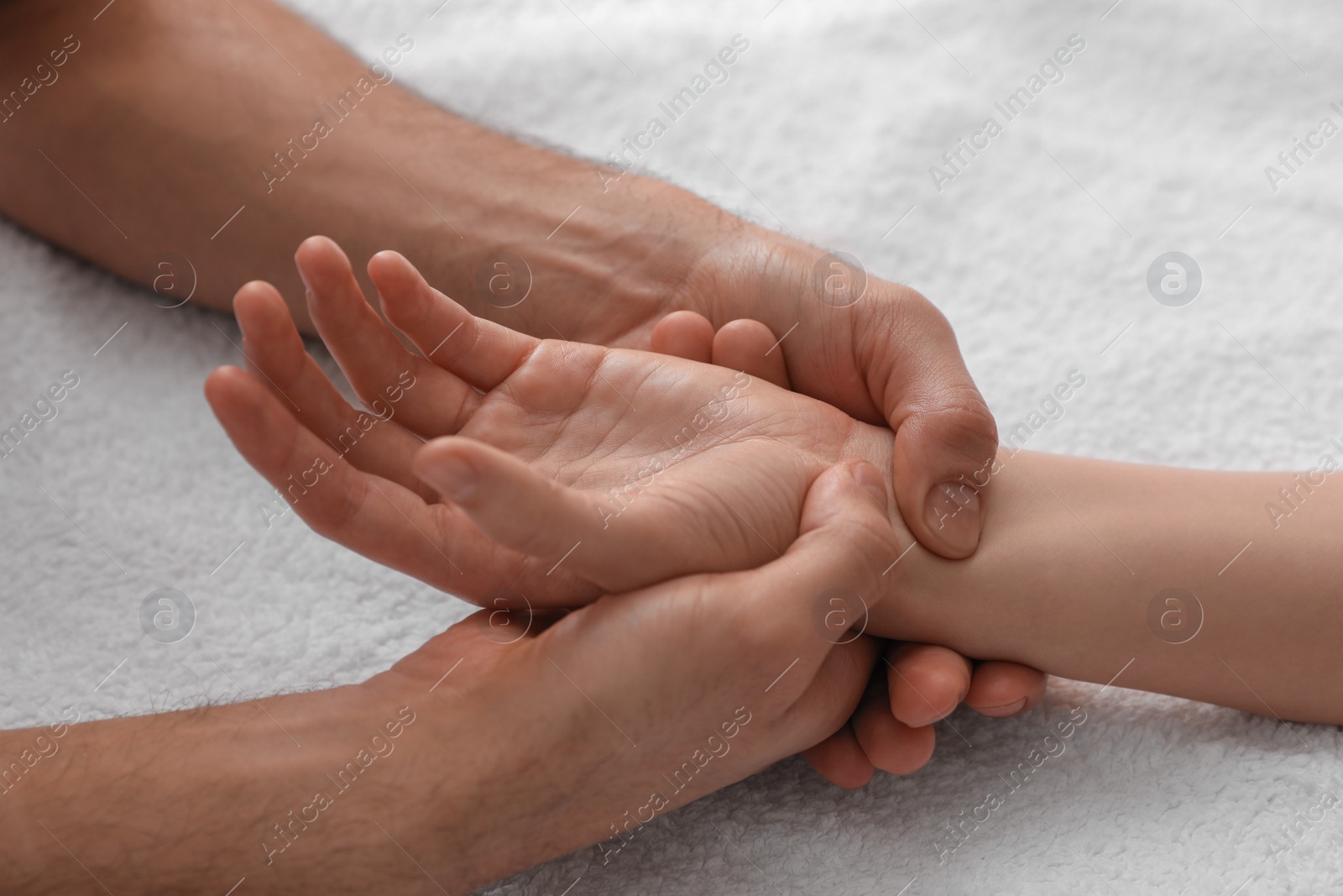 Photo of Woman receiving hand massage on soft towel, closeup