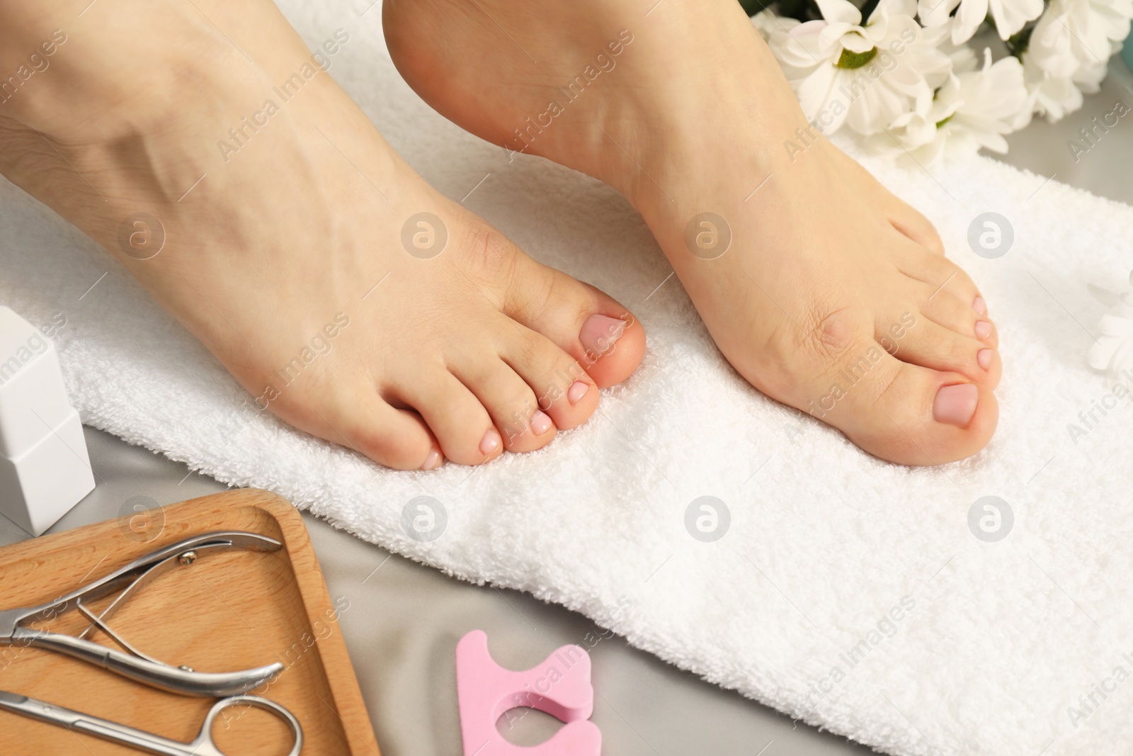 Photo of Woman with neat toenails after pedicure procedure on grey silky fabric, closeup