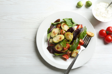 Photo of Delicious salad with roasted Brussels sprouts on white wooden table, flat lay