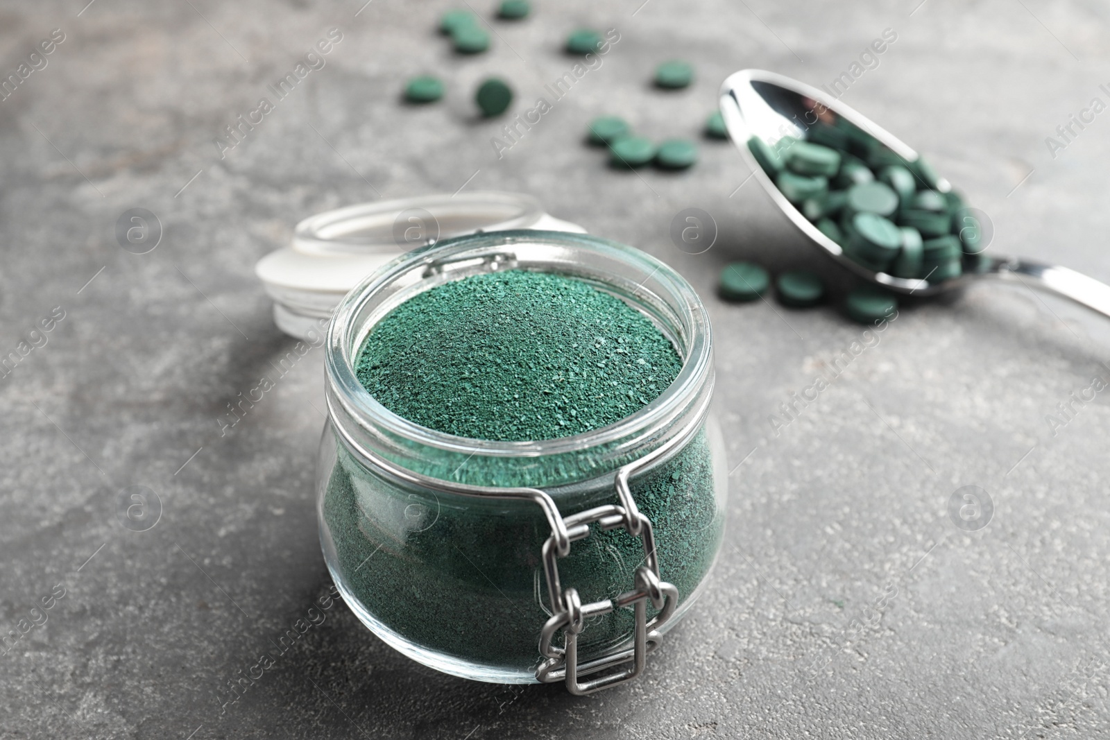 Photo of Jar of spirulina algae powder on table, closeup. Space for text