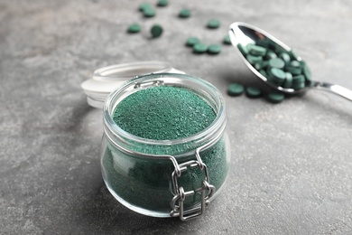 Photo of Jar of spirulina algae powder on table, closeup. Space for text