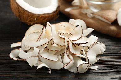 Photo of Pile of tasty coconut chips on black wooden table