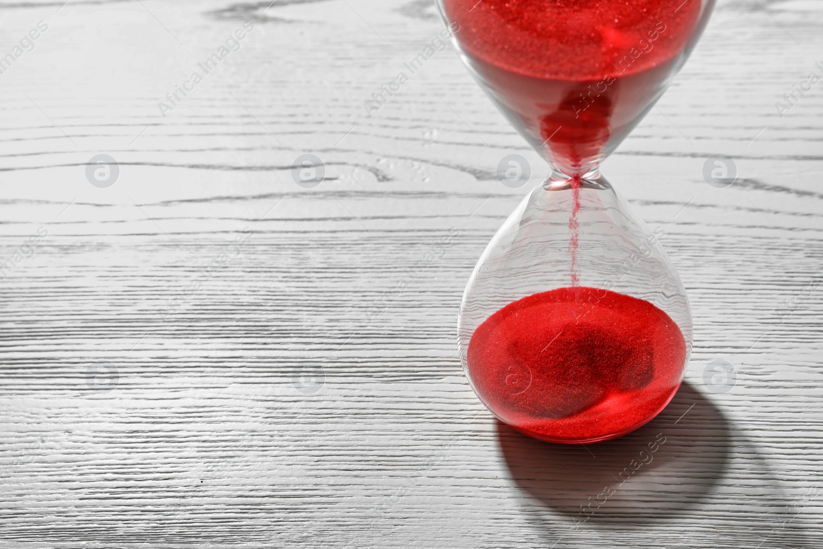 Photo of Hourglass with flowing red sand on wooden background. Time management