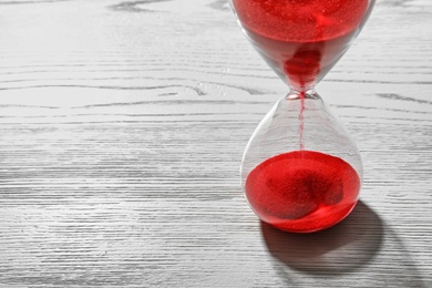 Photo of Hourglass with flowing red sand on wooden background. Time management