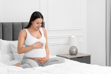 Beautiful pregnant woman on bed at home