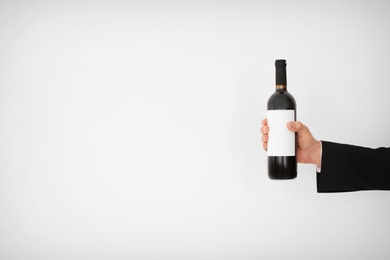 Photo of Man holding bottle of wine on light background