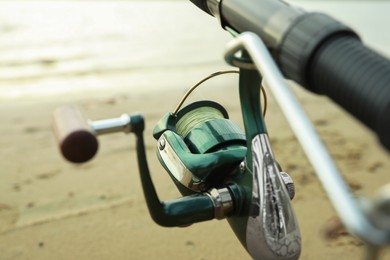 Photo of Fishing rod with reel near river, closeup