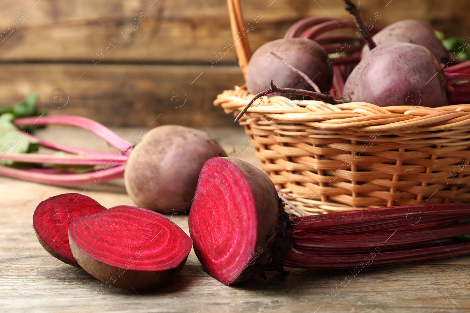 Photo of Cut and whole raw beets on wooden table