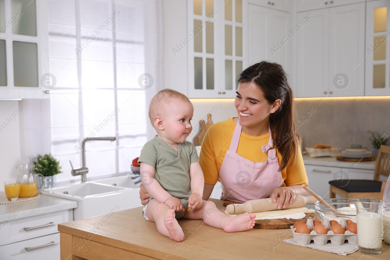 Photo of Happy young woman and her cute little baby cooking together in kitchen