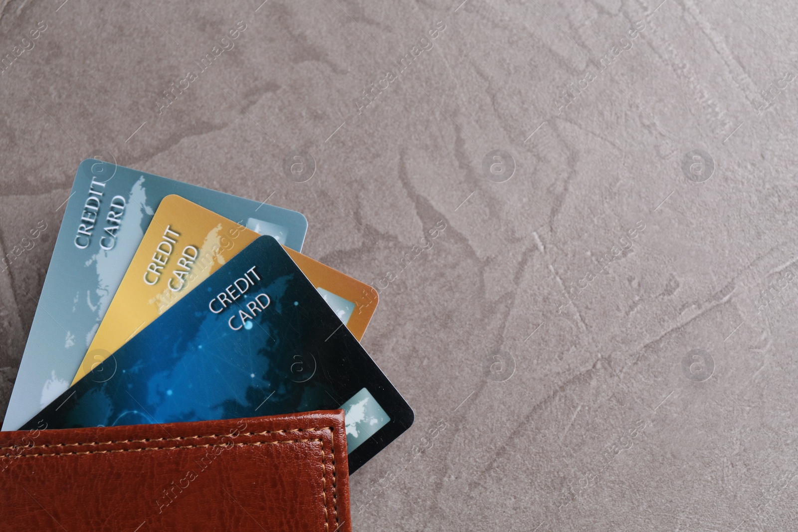 Photo of Credit cards and leather wallet on grey textured table, top view. Space for text