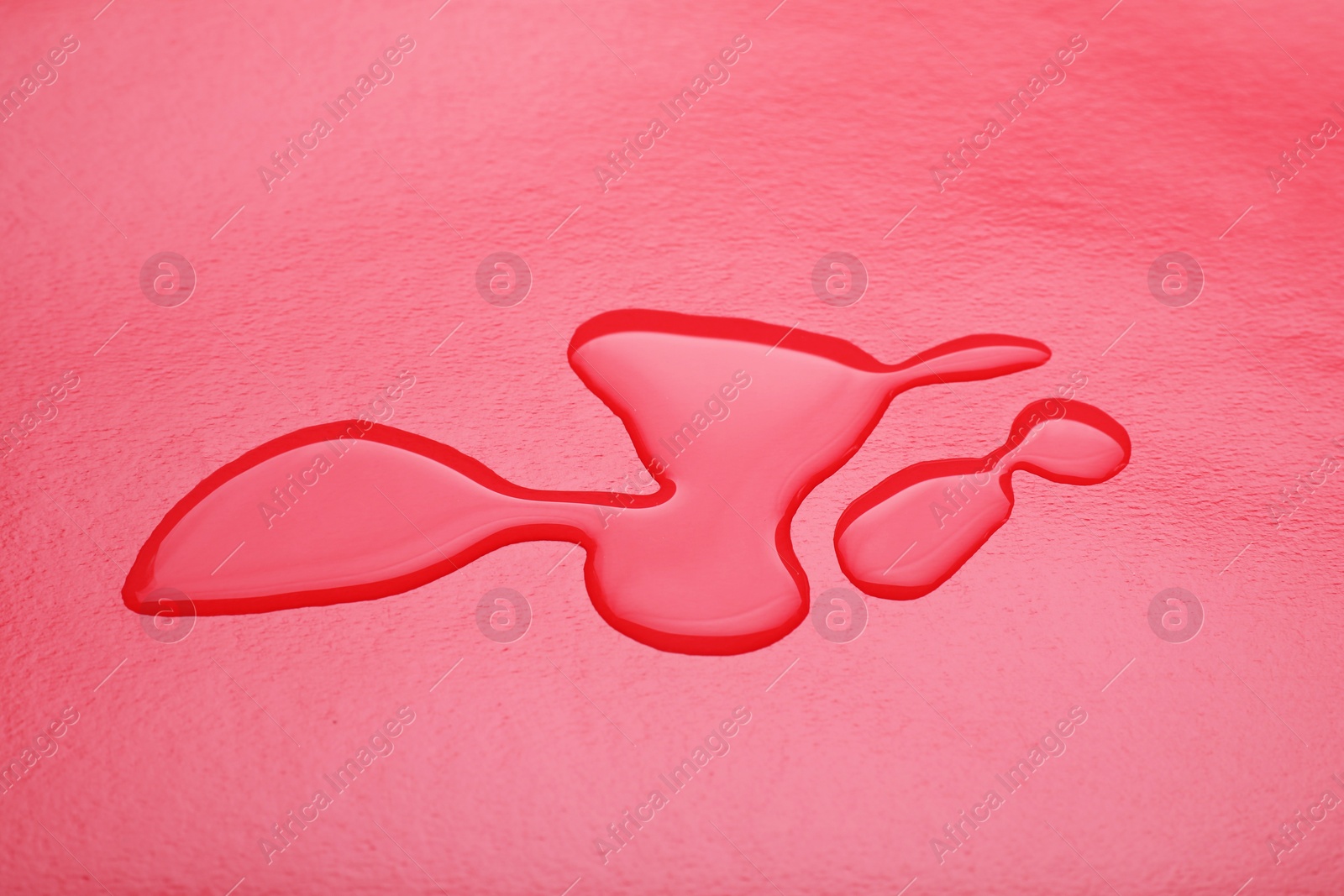 Photo of Puddle of water on red background, closeup