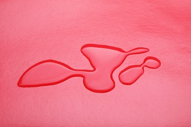 Puddle of water on red background, closeup