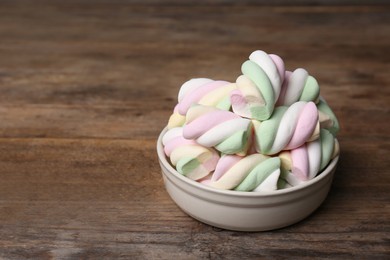 Photo of Bowl with colorful marshmallows on wooden table, space for text