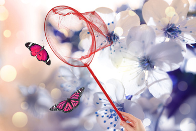 Image of Woman catching butterflies with net against blossoming flowers outdoors on sunny day, closeup
