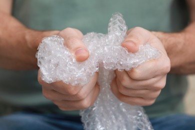 Photo of Man popping bubble wrap, closeup view. Stress relief