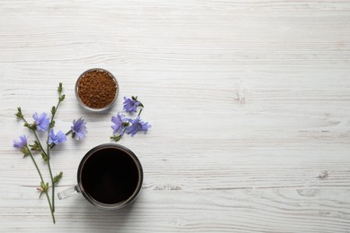 Glass cup of delicious chicory drink, granules and flowers on white wooden table, flat lay. Space for text