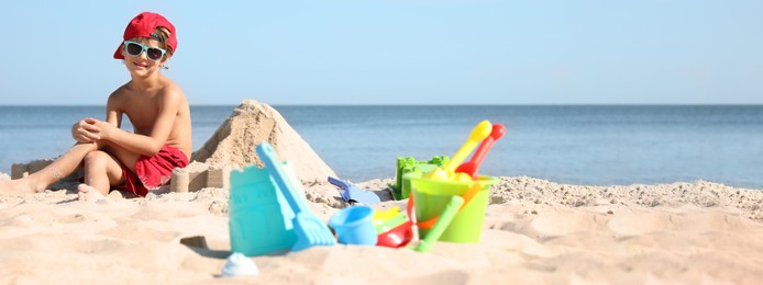 Image of Cute little child and plastic toys at sandy beach on sunny day. Banner design