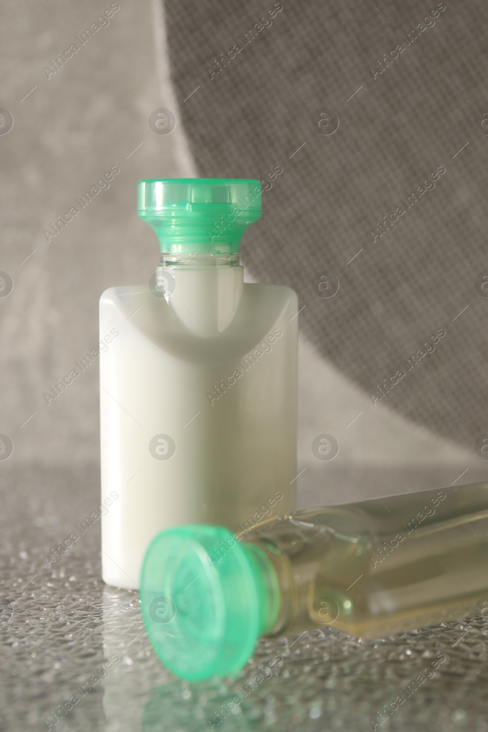 Photo of Mini bottles of cosmetic products on grey textured table