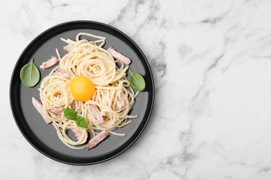 Photo of Plate of tasty pasta Carbonara with basil leaves on white marble table, top view. Space for text